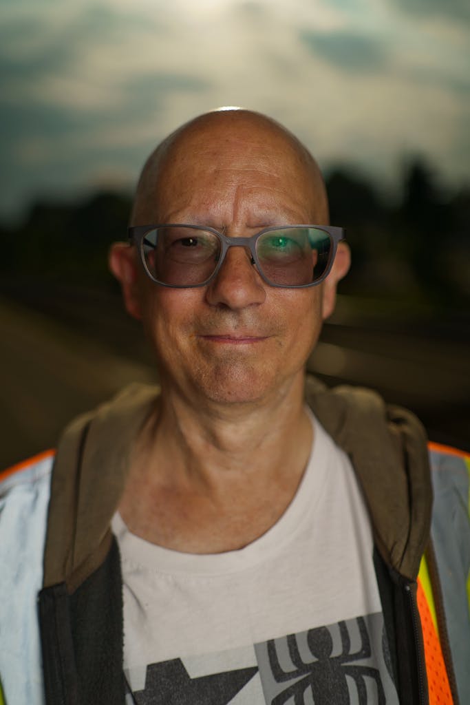 A man with glasses and a safety vest standing in front of a train