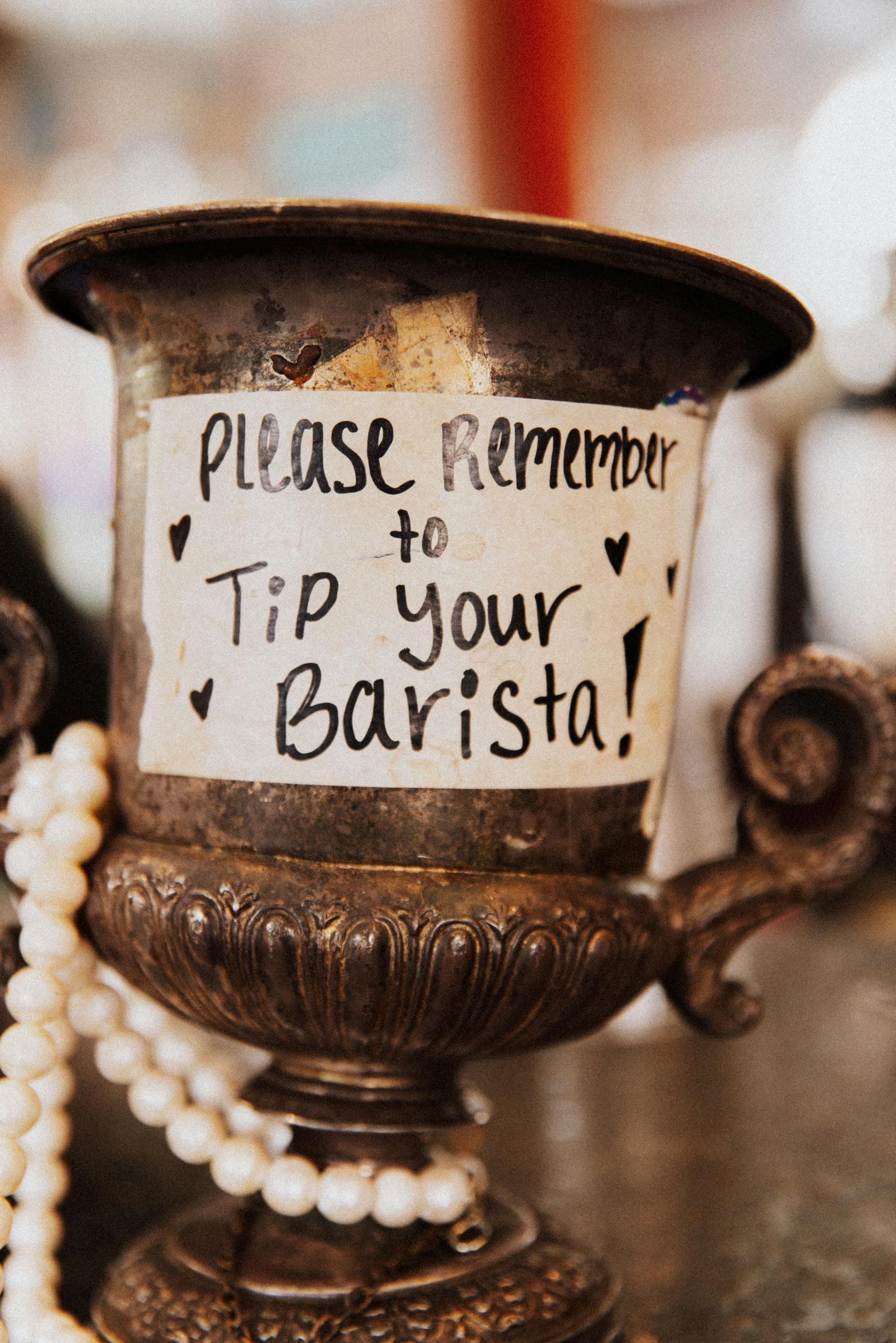 A vintage container encouraging patrons to tip baristas, adorned with pearls.