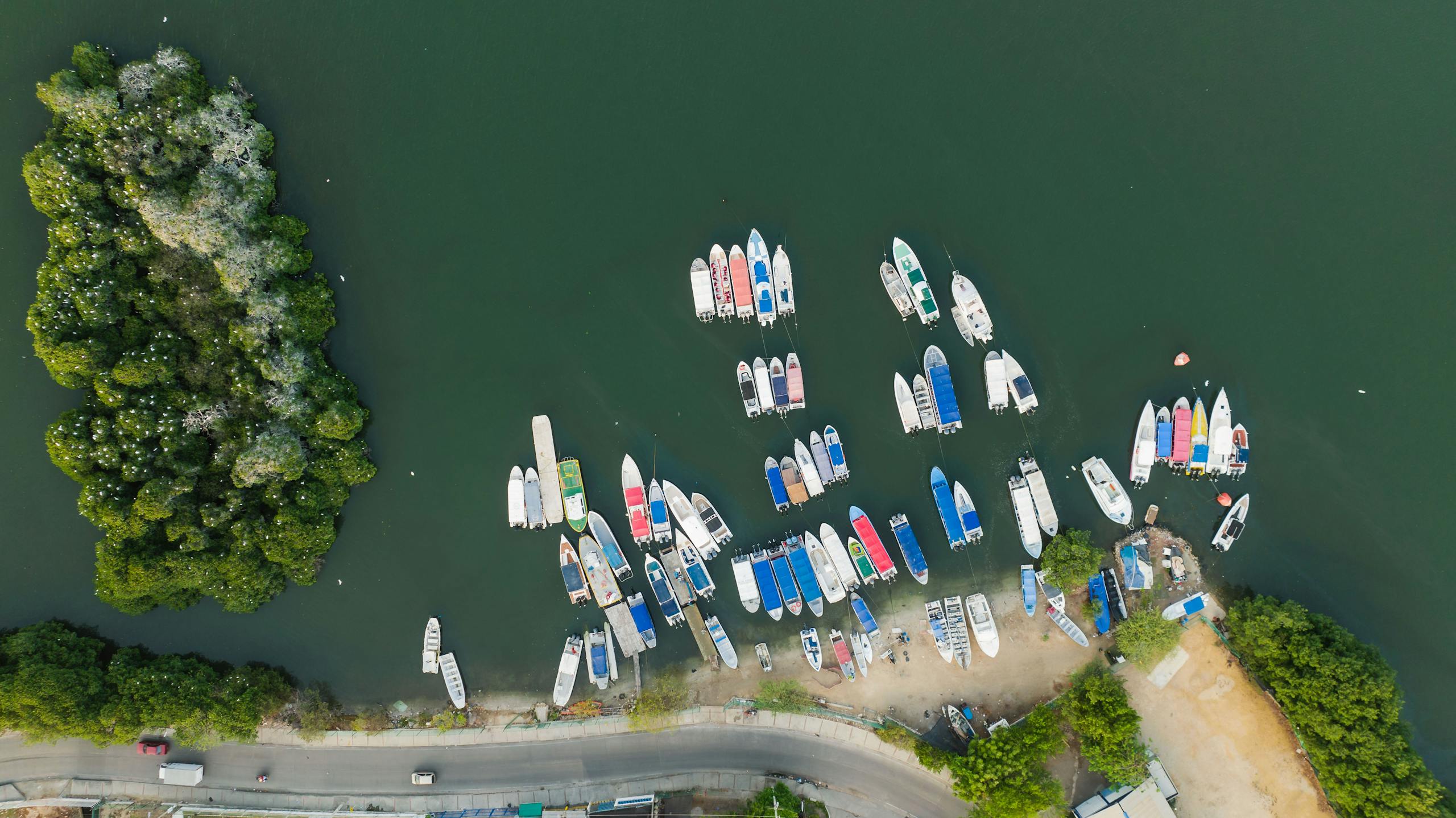 Aerial photo capturing boats moored on a calm river surrounded by lush greenery.