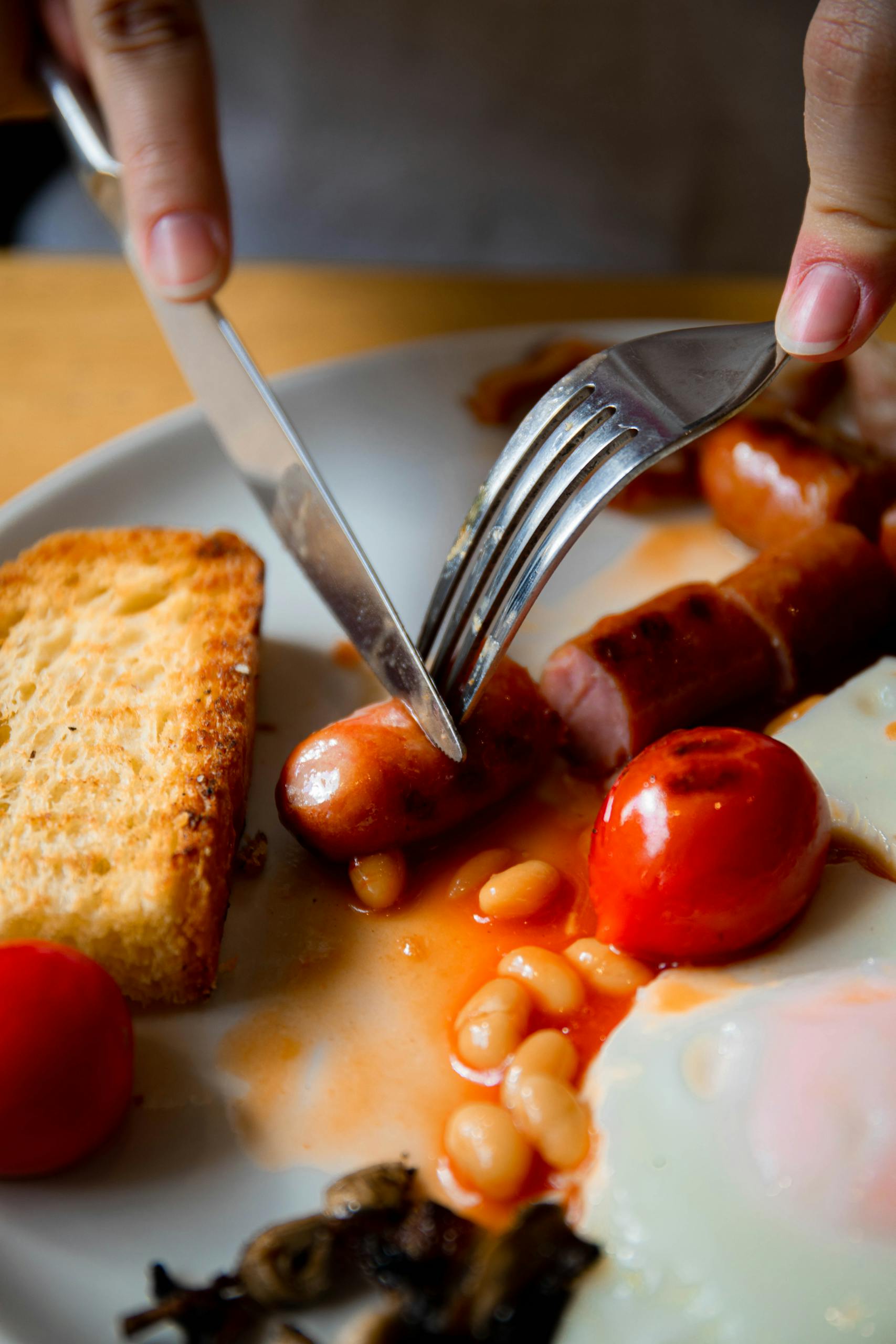 Delicious full English breakfast with sausage, beans, tomato, and toast.