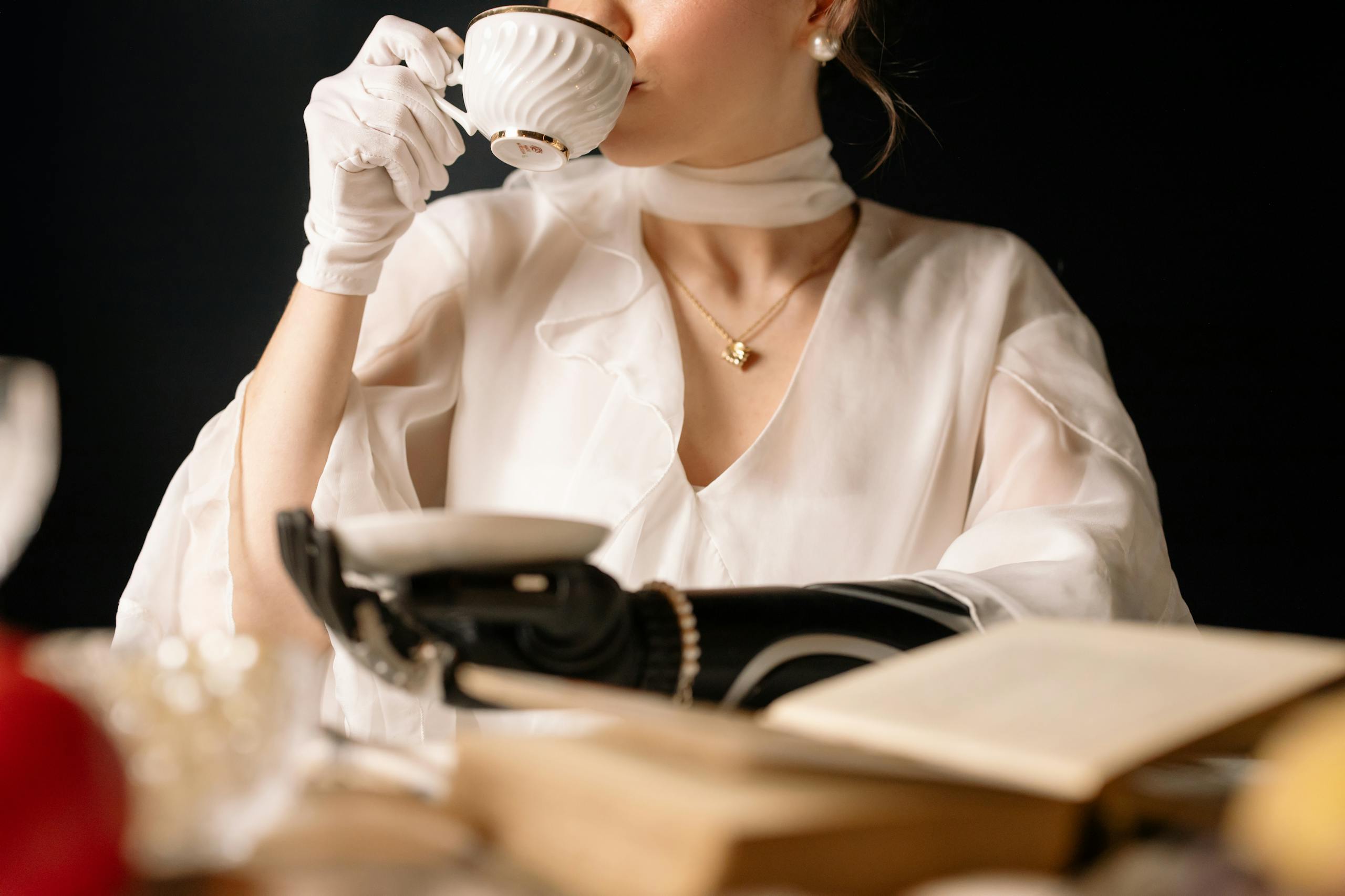 Sophisticated woman with a prosthetic arm enjoys tea, showcasing elegance and technology.
