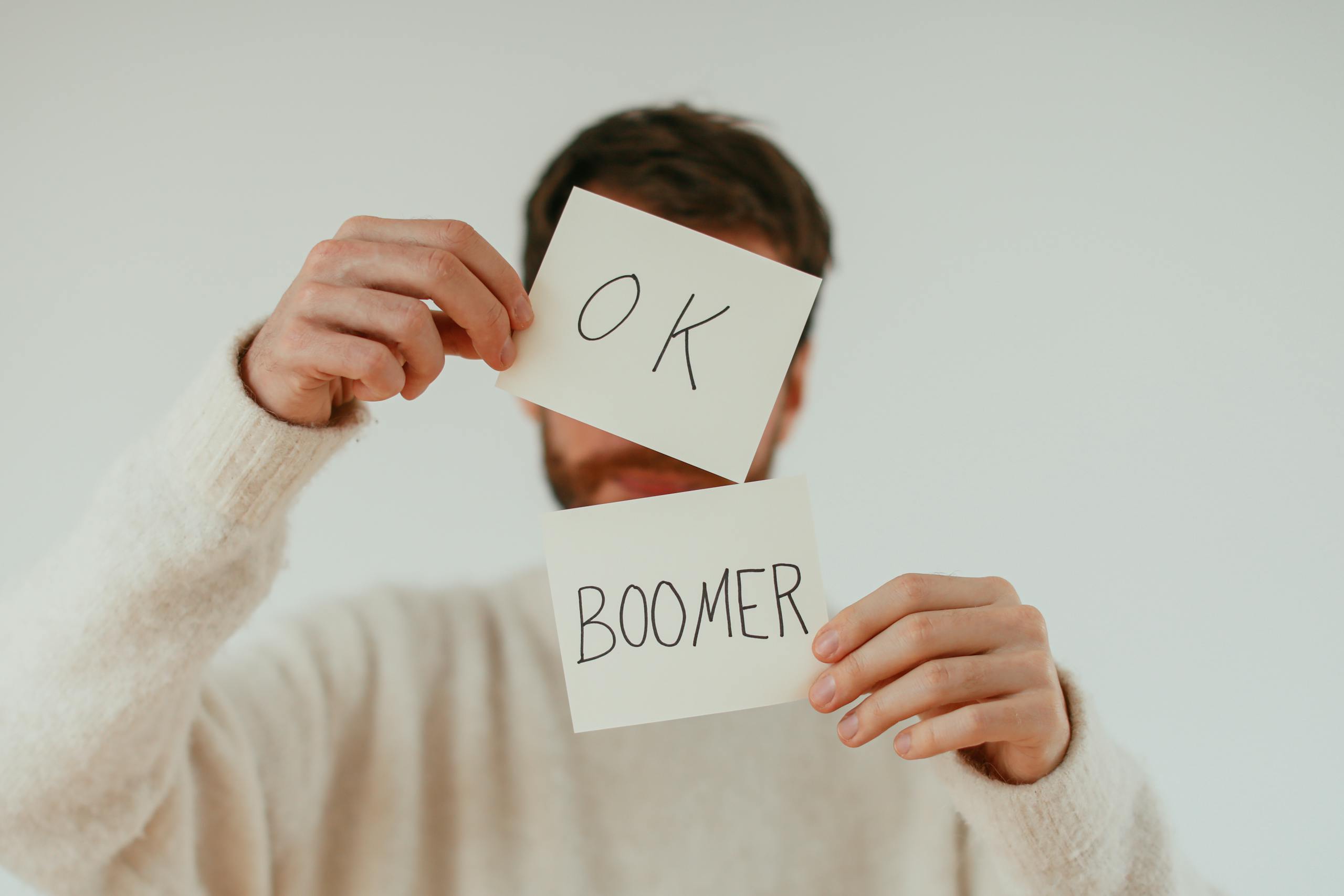 A person holding two cards with 'OK Boomer' written in bold text.