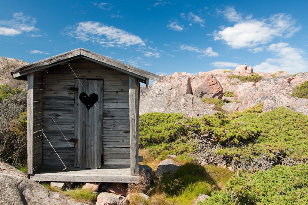 Charming rustic wooden cabin with heart-shaped door in rocky countryside.