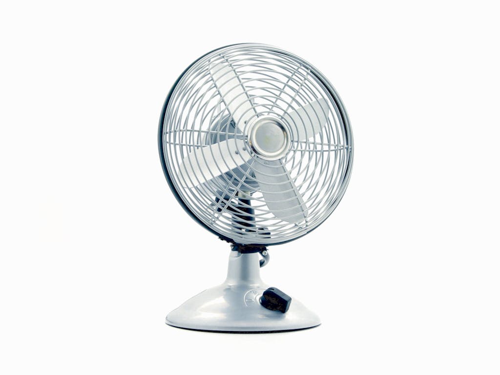 Close-up of a classic electric desk fan against a white background, showcasing retro design.